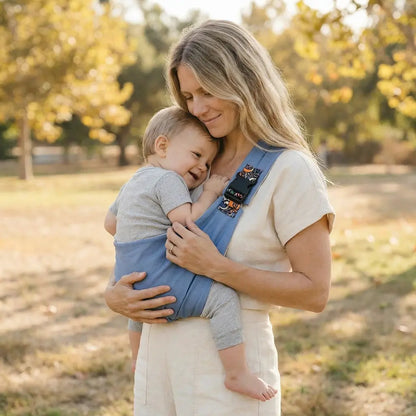 Needella CozyCarry Hüfttrage in Hellblau, Eltern tragen ihr Baby entspannt im Alltag