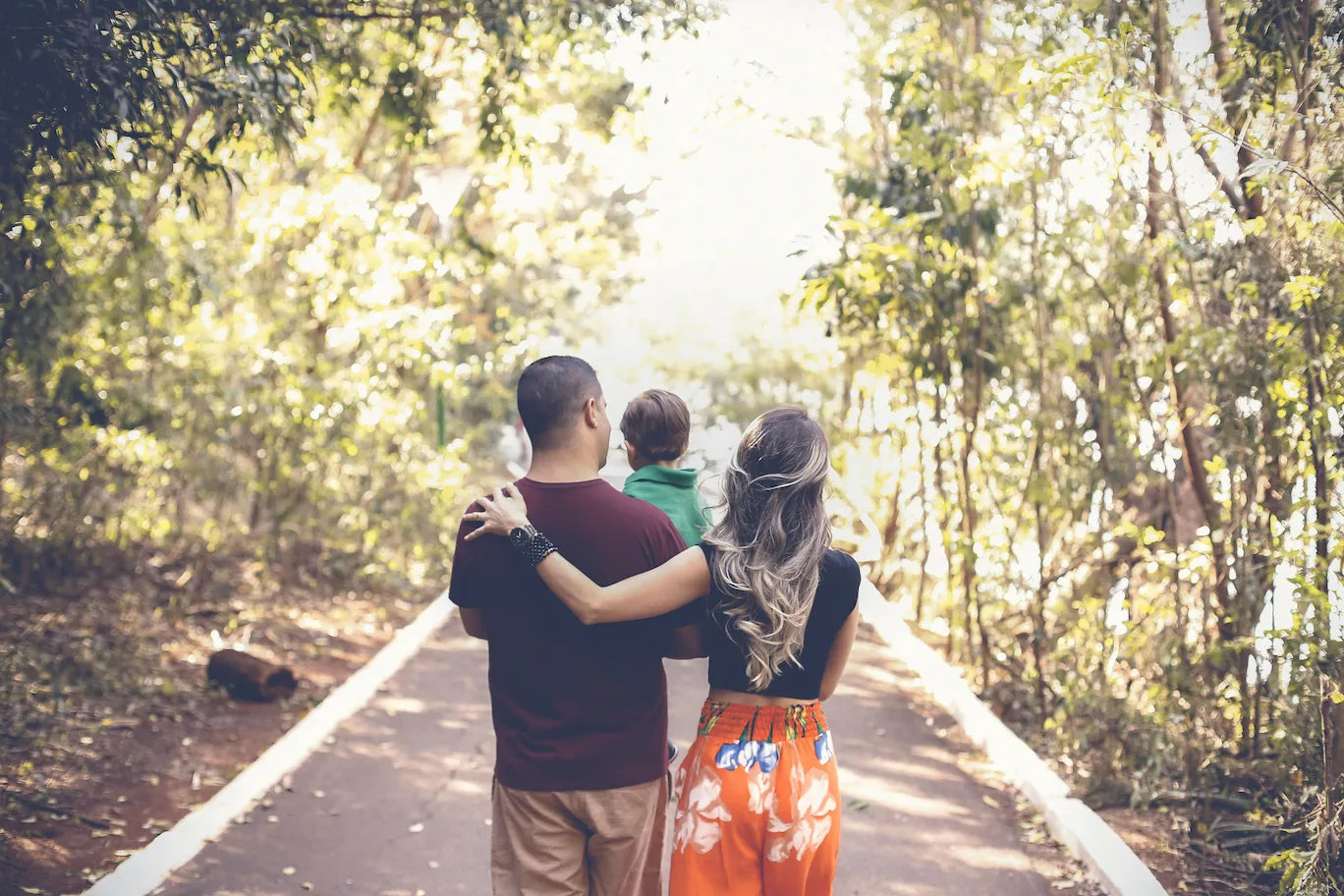 Familie mit Kind beim Spaziergang im Wald, Eltern genießen einen gemeinsamen Moment im Alltag