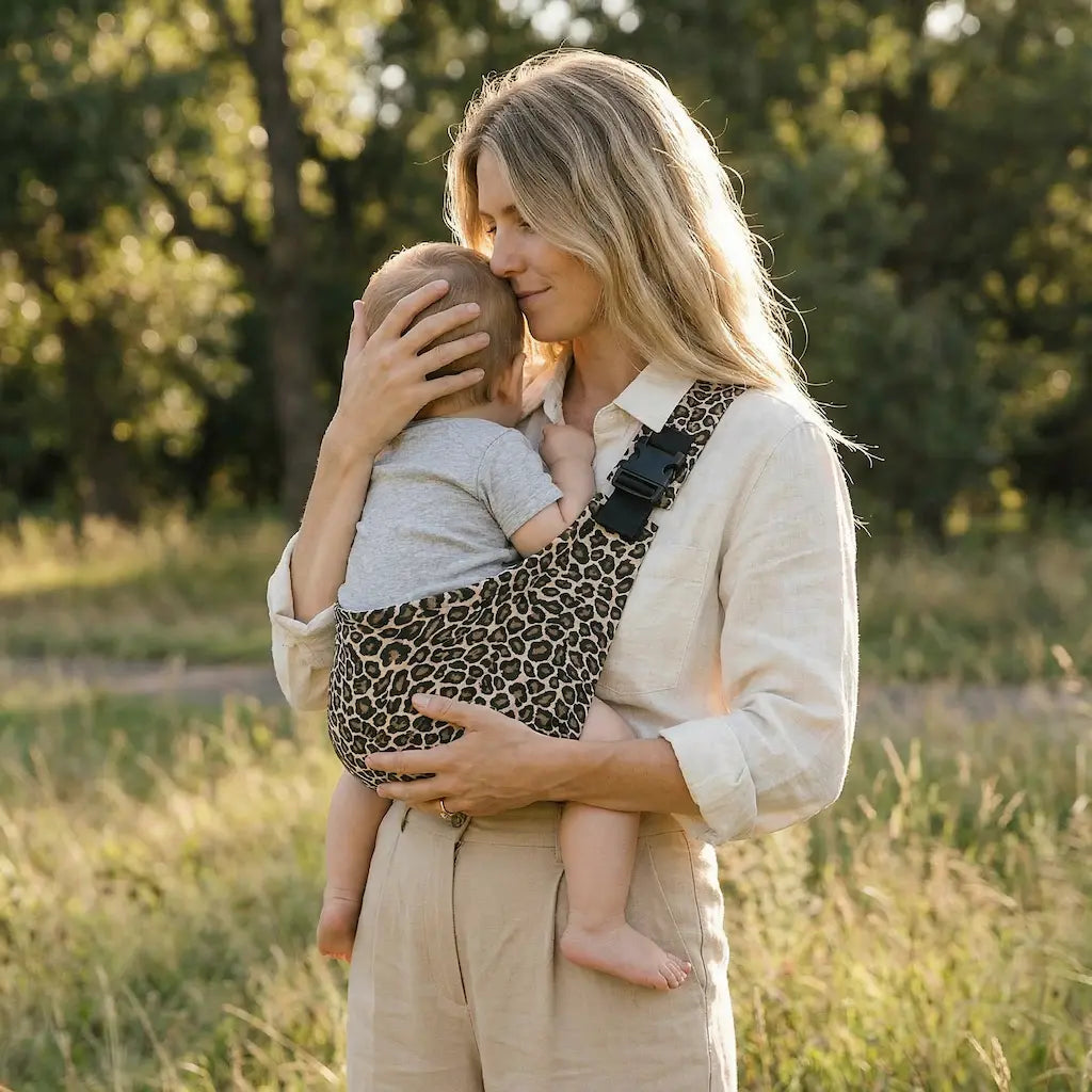 Needella CozyCarry Hüfttrage in Leopard, Mutter trägt ihr Baby nah am Körper im Alltag