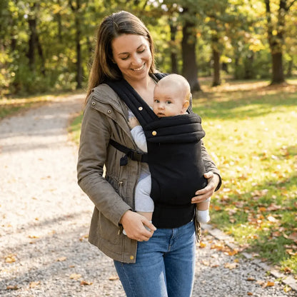 Needella Embrace Babytrage in Schwarz, Mutter trägt ihr Baby nah am Körper im Alltag